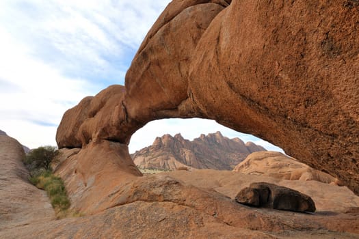 The Bridge, a natural arch at Spitzkoppe, Namibia with the Pondok mountains peeping through