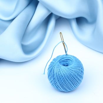 thread on blue silk isolated close up