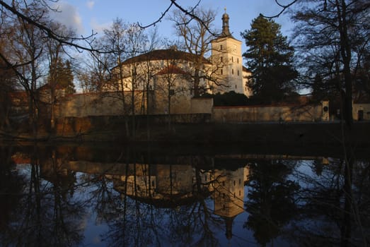 Beautiful castle in Breznice is lit by a setting sun and is reflecting in water. The Czech Republic