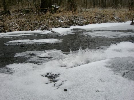 River is covered by icicles and water flows under them with its stream       