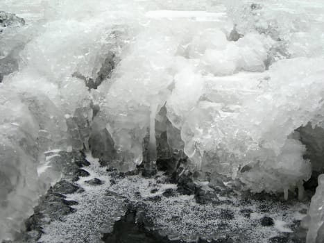 Brook is covered by ice and water flows under them with a small strem                