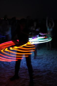 SIESTA KEY, FLORIDA - MAY 22: Dancers twirling colored lights are seen as silhouettes at a drum circle on Siesta Key Public Beach near Sarasota, Florida, May 22, 2011.  A slow shutter speed gives motion blur to the dancers and colored lights as they whirl on the sand.