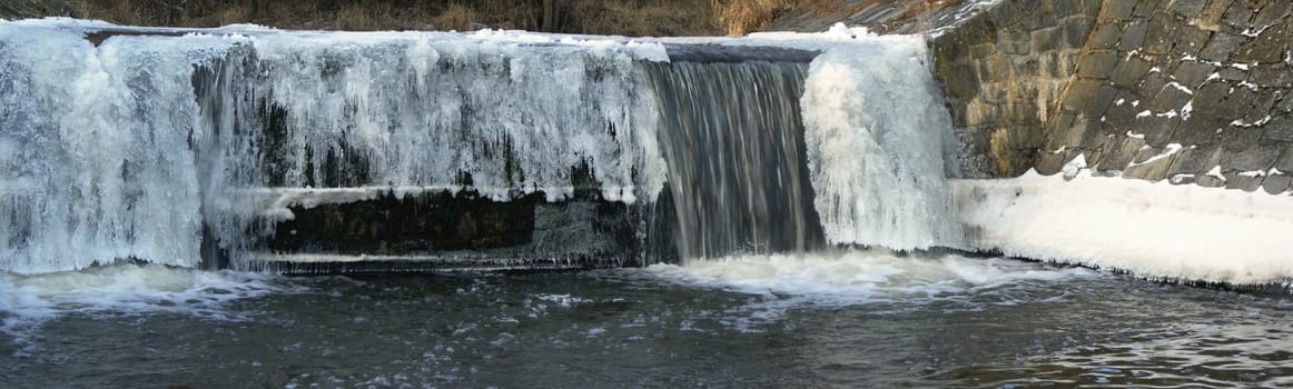 Flowing water in a brook is covered by clear ice