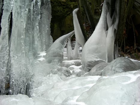 Flowing water in a brook is covered by clear ice