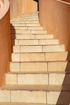 Warm beige stones wind upwards towards the top of a staircase in Belize City, central America