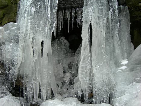 Flowing water in a brook is covered by clear ice