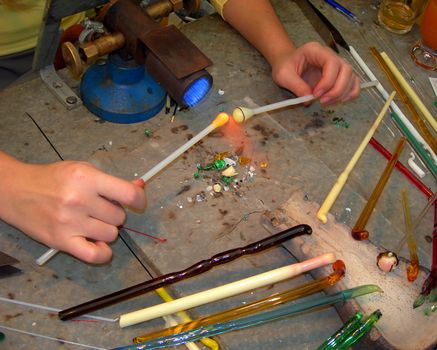 Hands of a young woman are creating beautiful jewels from glass          