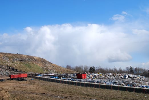 Red container full of waste in the trash dump