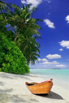 Tropical Maldivian beach with palms and wooden fising ship