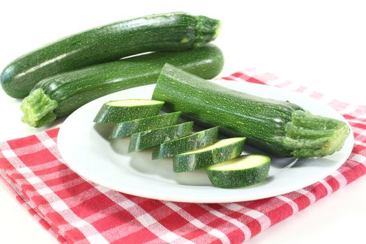 fresh sliced zucchini on a plate with napkin in front of light background