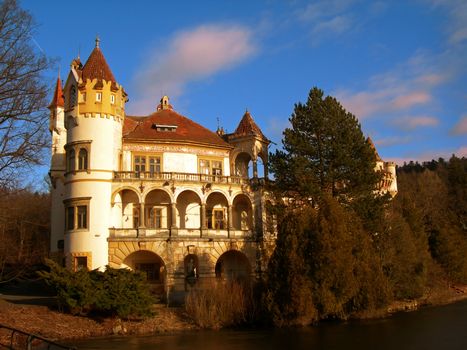           Beautiful romantic castle with river and forest at sunset