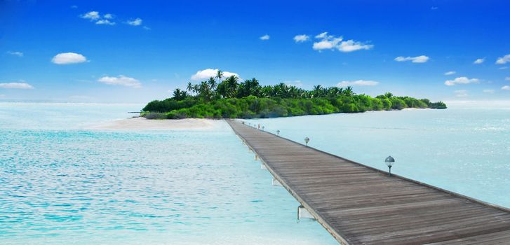 Jetty leading to he beautiful Maldivian atoll with coconut palms 