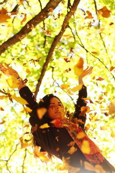 woman drop up leaves in autumn park