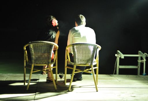 young romantic couple sitting on the pontoon with a glass of wine