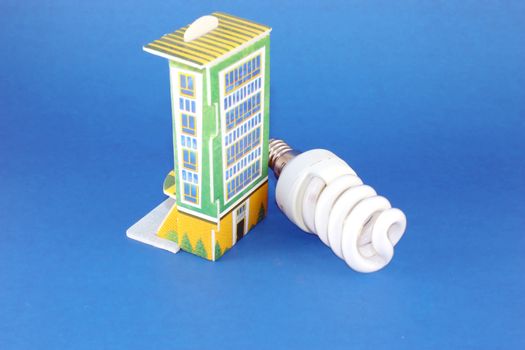 Fluorescent lamp bulb with model of house over blue