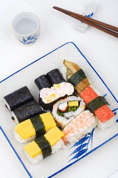 varieties of sushies with cup and chopstick