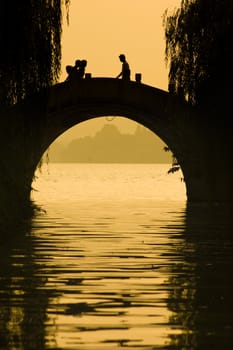 silhouette of people walking on the bridge in xihu,hangzhou