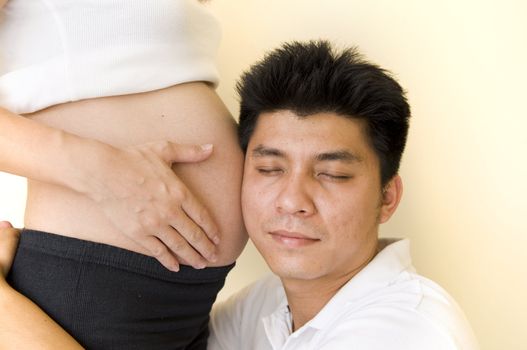 an asian father listening to womb of an asian mother