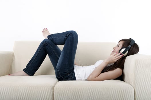 beautiful young asian listening to music on a sofa
