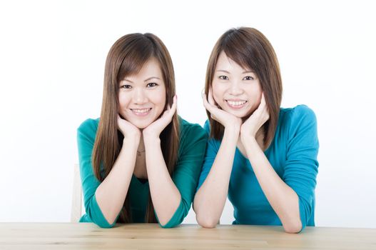 two asian adults sitting on a table and smiling