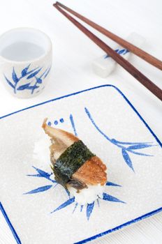 sushi with chopstick on a plate and cup