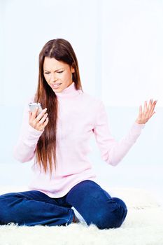 angry young woman using mobile phone at home