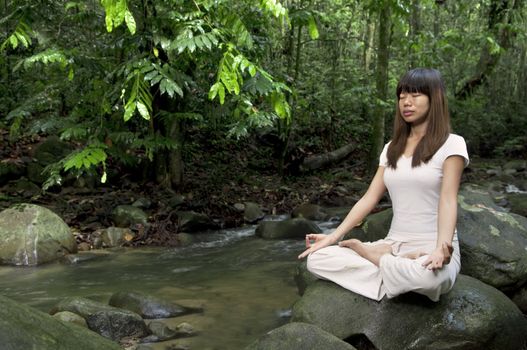 asian girl performing yoga with green forest background 