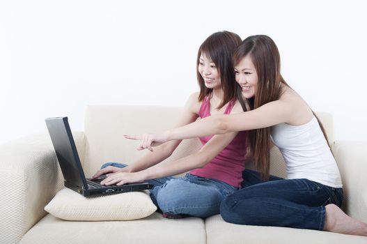 asian girls using laptop sitting on sofa