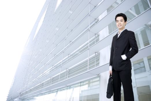 young asian business man holding a suitcase with office background 