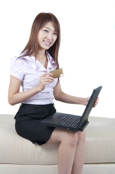 Asian female online shopping, sitting on sofa.
