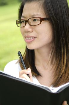 asian college girl holding a pen and a notebook