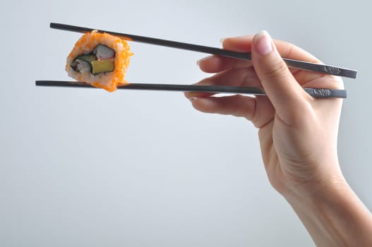 hand with chopstick holding sushi