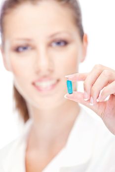 Pretty female nurse holding blue pill, focus on pill