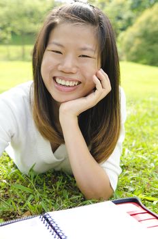 asian girl smiling and writing on outdoor