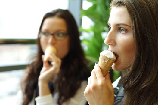happy smiling women on foreground licking ice cream 