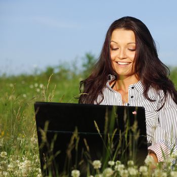 girl with laptop on green grass