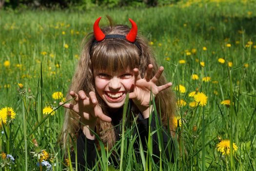 little devil girl in a green dandelion field