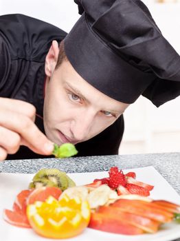 chef in black uniform decorating delicious fruit plate