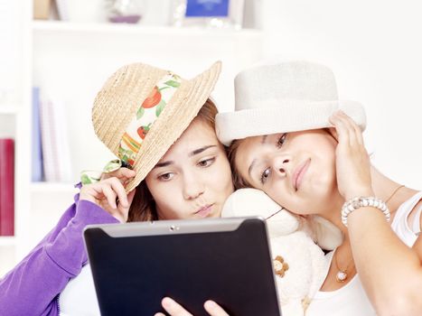 Two happy teenage girls having fun using touchpad computer