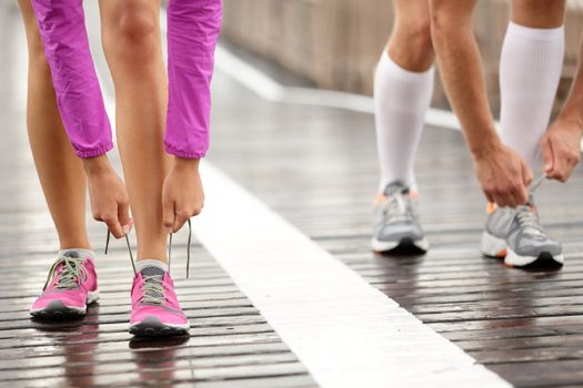 Runner feet. Running couple closeup of running shoes. Woman barefoot running shoes in foreground. Couple jogging on Brooklyn Bridge, New York.