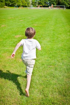 A young boy running across a playing filed