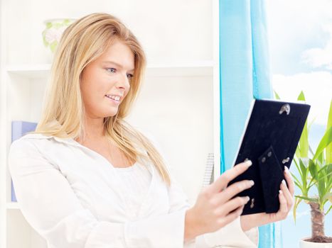 Happy woman holding frame of photo at home