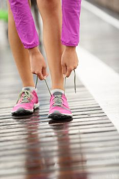 Running shoes. Barefoot running shoes closeup. Woman tying laces before jogging in minimalistic barefoot running shoes on Brooklyn Bridge, New York, USA.