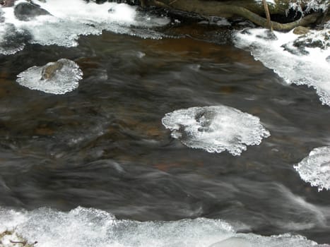                  Brook is covered by ice and water flows under them with a small strem                  