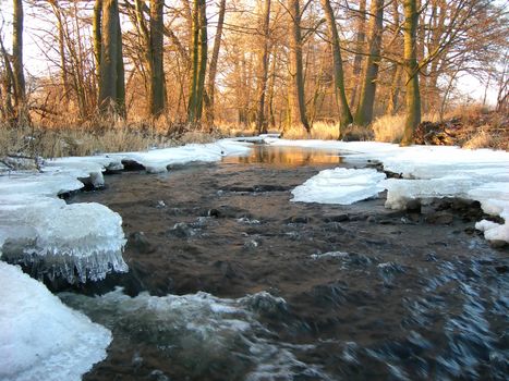           River is covered by icicles and  is lit by a sun