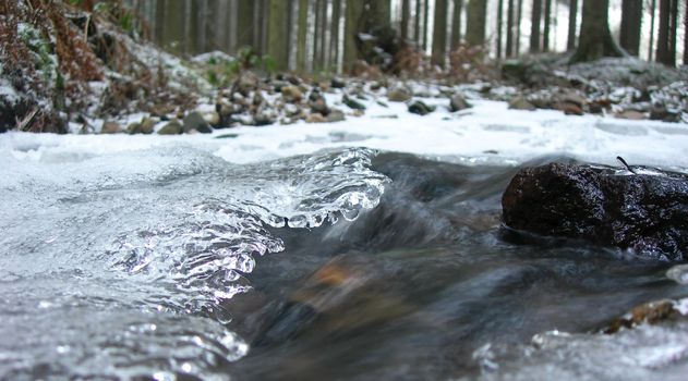 Water of a brook in the winter is covered by ice. Under it flows a crystal clear spring 