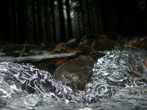         Brook is covered by ice and water flows under them with a small strem                           