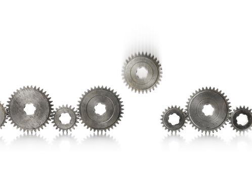 A row of old metallic cog gears being filled with one blurry falling gear.