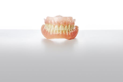 Old dirty dentures on grey background.
