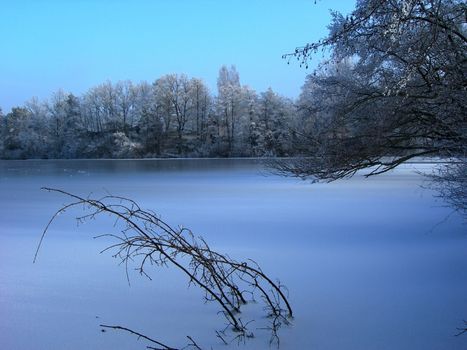 Frozen lake in winter with trees on the bank